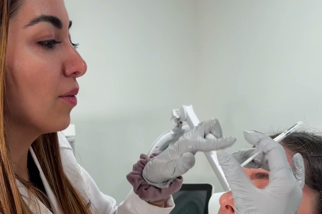 Rocio Romero, PA-C, in a white coat and gray gloves, performs an injection on a client's forehead at ROW 89