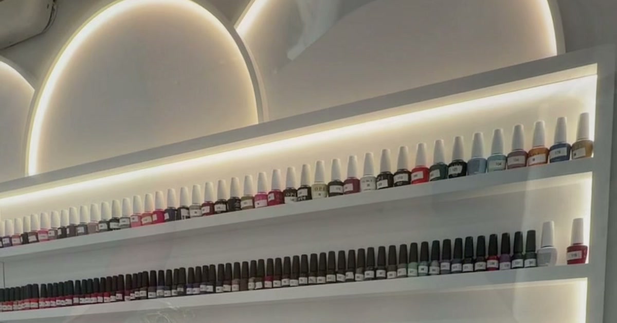 The backlit nail polish wall at ROW 89's first-floor nail bar: two long shelves of gel polish bottles running from pinks and reds to deep browns and near-black shades.