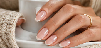 Hand with almond-shaped sheer pink gel nails and a milky white French tip holding a white mug