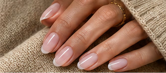 Hand with short milky white French-tip nails resting on a beige knit sweater